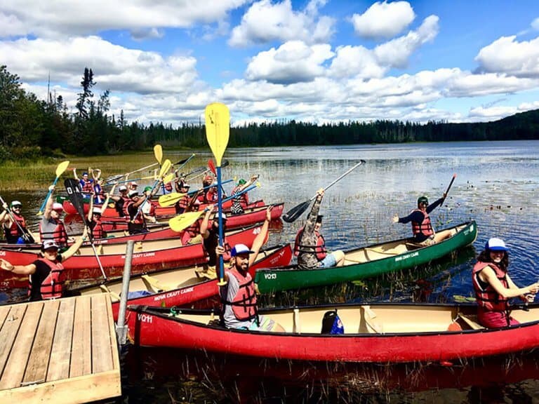 Team building group paddling red canoes on an Algonquin lake