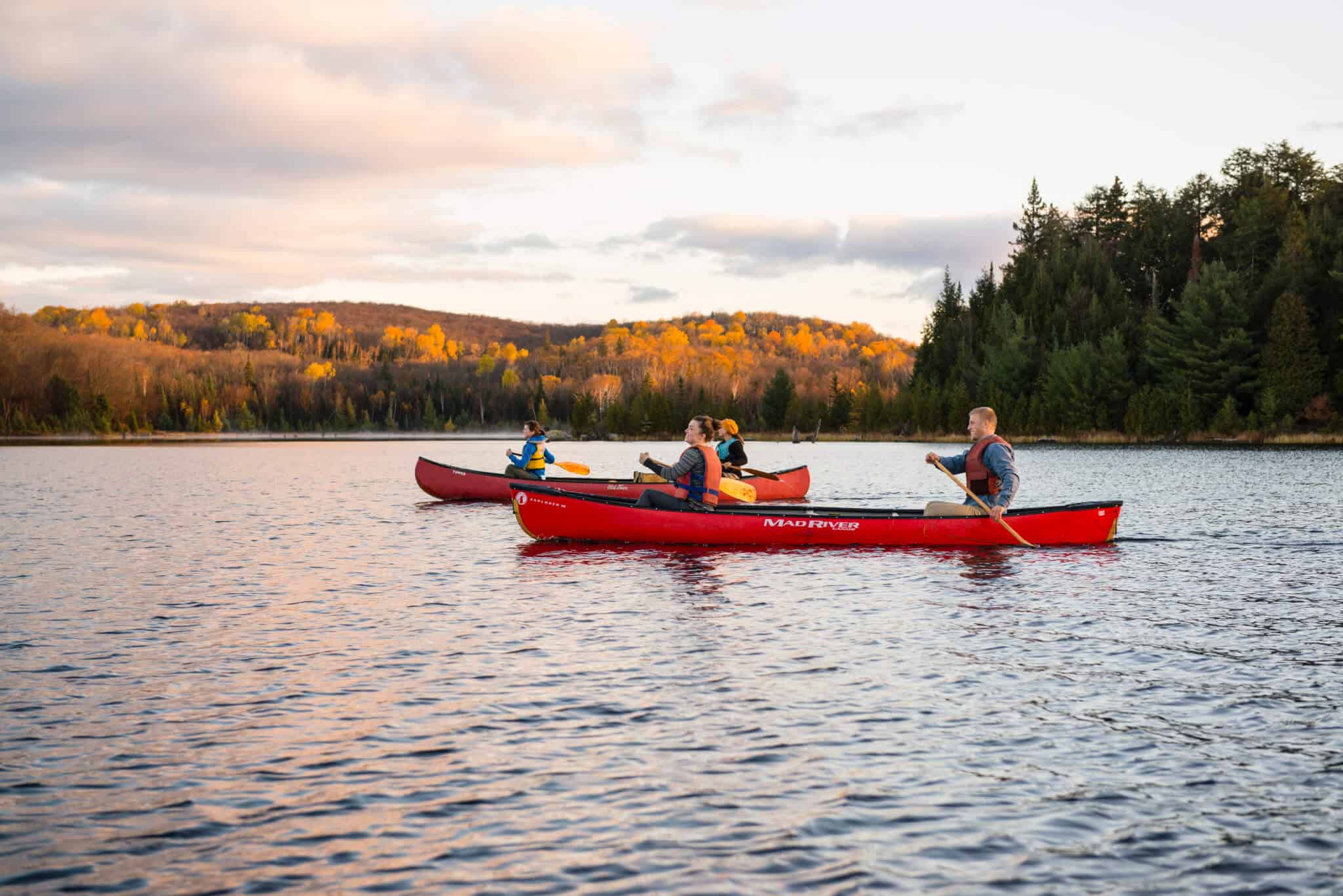 2 red canoes on a lake with in the background Fall colours