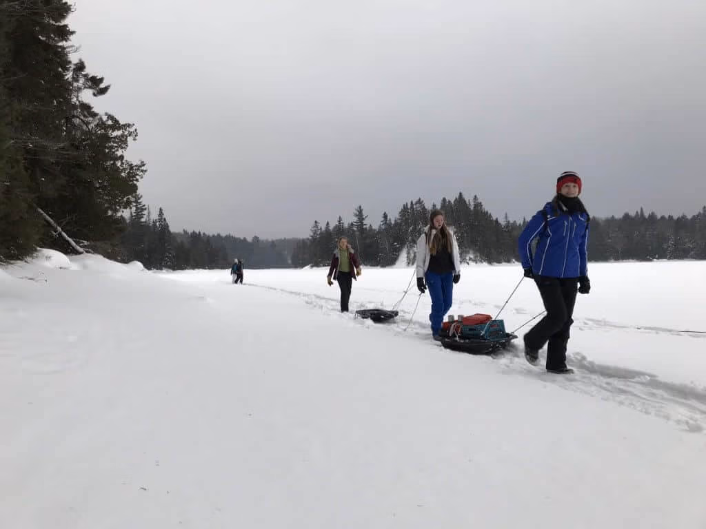 Students hauling toboggans across a frozen lake on a Duke of Edinburgh winter expedition