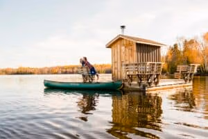 Couple standing on the the floating sauna enjoying the fall colours at Algonquin