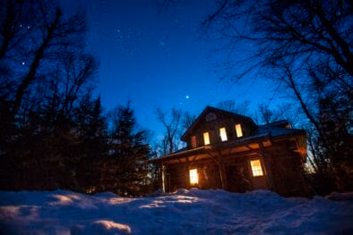 Algonquin Log Cabin in Winter surrounded with a sky full of stars