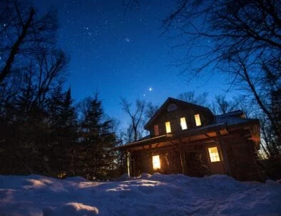 Algonquin Log Cabin in Winter surrounded with a sky full of stars