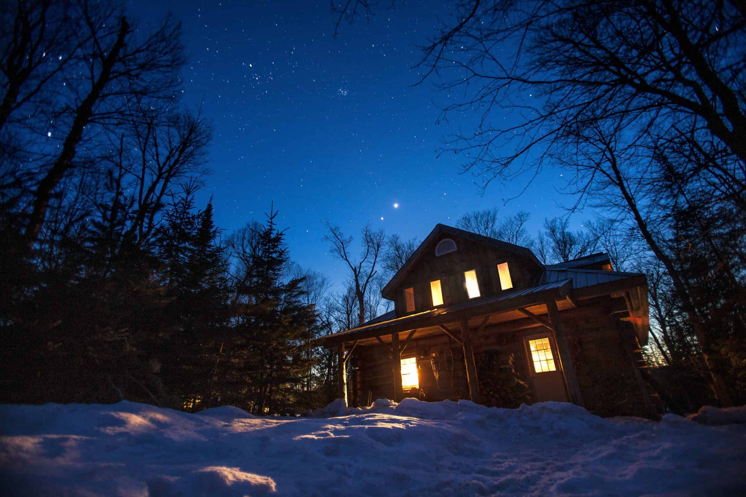 Algonquin Log Cabin in Winter surrounded with a sky full of stars
