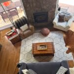 Living romm at Hondoo Cottage looking down from second floor. Fireplace wall is flanked by two sliding doors for walkouts to patio and lake beyond.