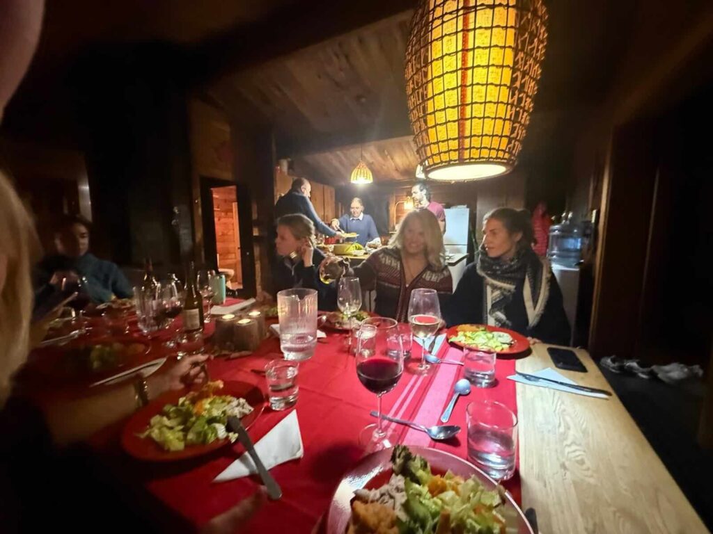 Guests sharing dinner at a long candlelit table in a wood-panelled Algonquin cabin