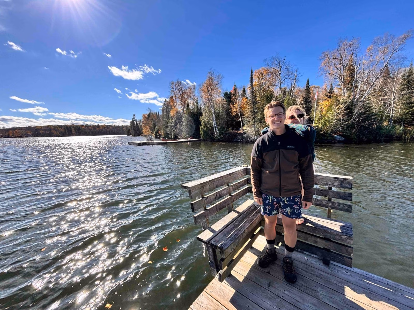 Ryan and Rene smiling on the floating sauna dock on an Algonquin lake in fall colours