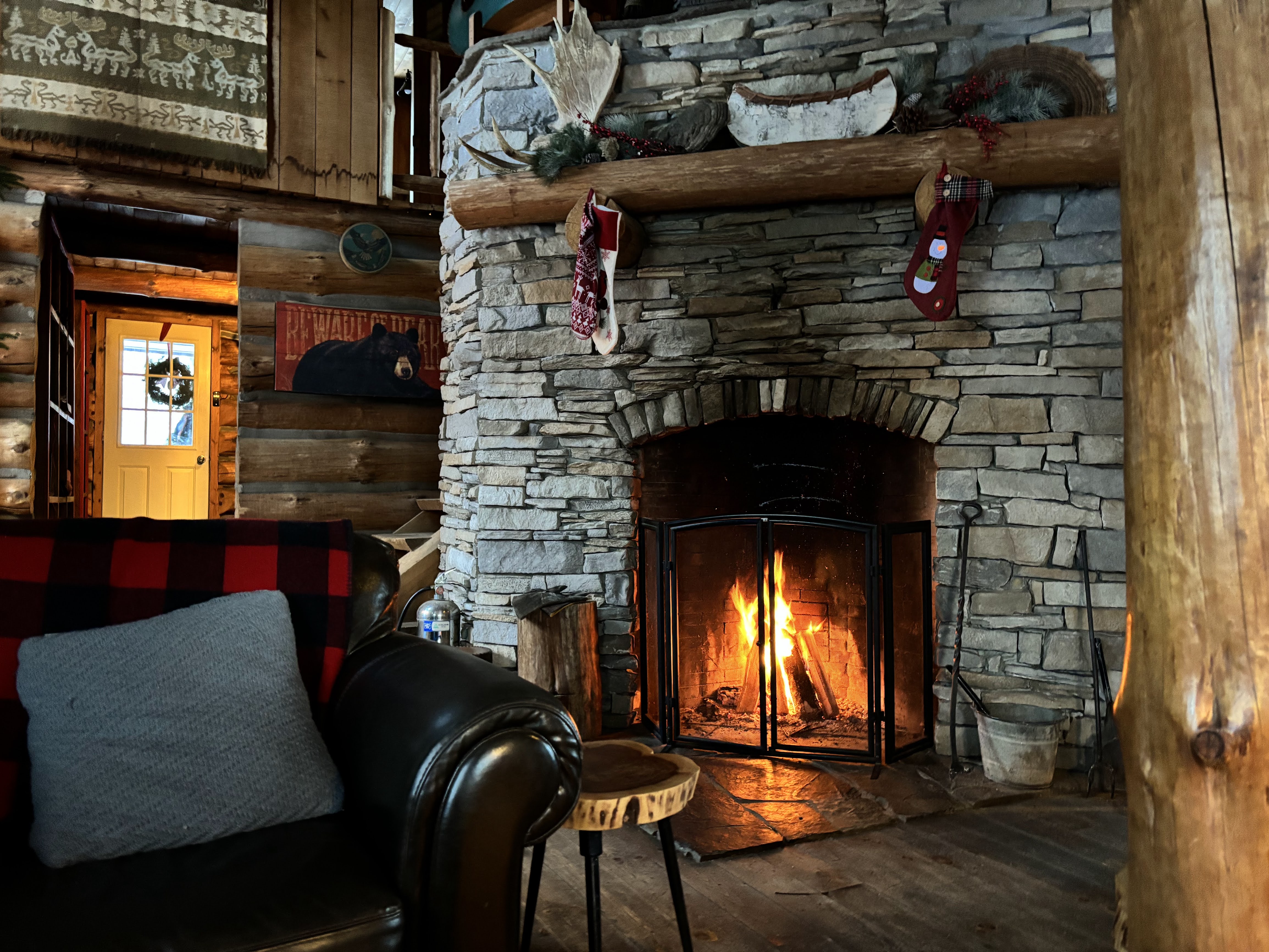 Wood-burning stone fireplace with stockings on the log mantel at the Algonquin Log Cabin